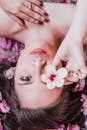 Elegant photoshoot featuring a woman holding a pink flower amidst petals.